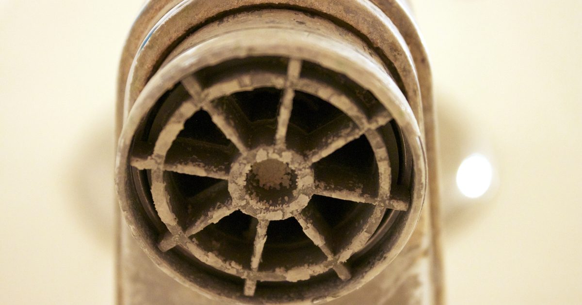 Close-up of a faucet aerator crusted with white limescale from hard water